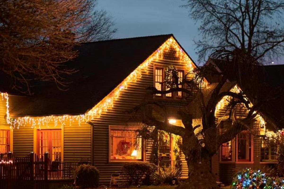 Casa con luces de navidad cálidas bordeando el techo de noche